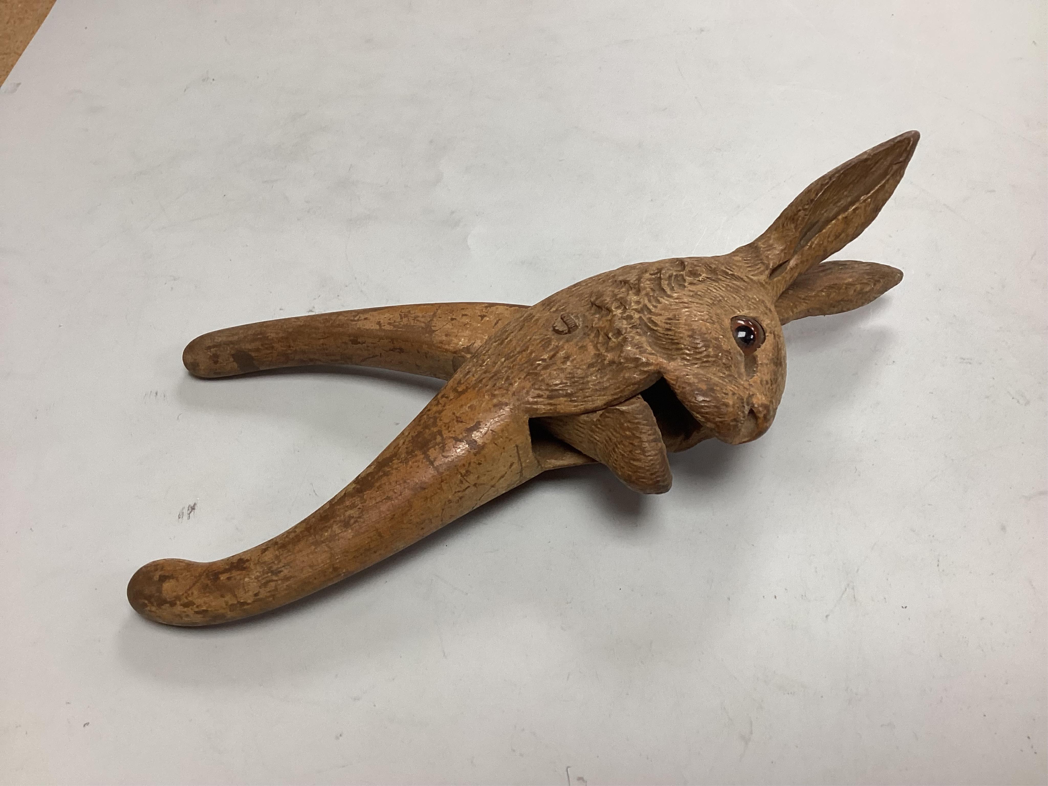 A pair of late 19th century Black Forest nutcrackers carvdd as a hare with glass eyes (loss) signed Champlex and a screw action novelty nutcracker carved with the head of a smiling man- 16.5cm high